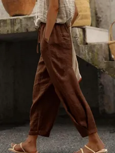 Detail of brown cotton linen trousers with drawstring elastic waist and side pockets.
