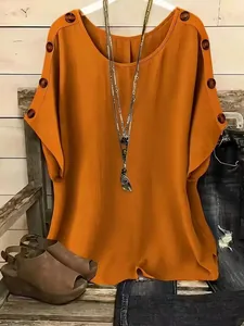 Close-up of casual orange short sleeve top featuring stylish decorative shoulder button details