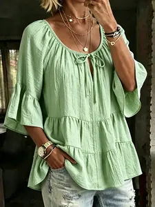 Detail view of a light green ruffled tier blouse featuring textured fabric and 3/4 bell sleeves.