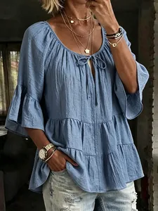 Detailed view of women's blue ruffled blouse featuring a tie-neck and textured bell sleeves.