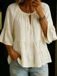 Loose-fitting white tiered blouse with ruffled sleeves and tie-neck detail