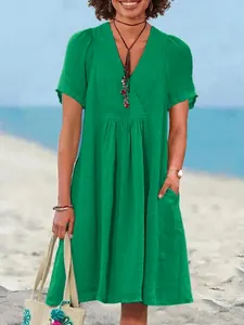 Detail of a green cotton linen V-neck dress with gathered waist and short sleeves