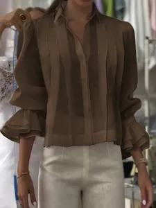 Detalle de blusa plisada marrón con elegantes puños de volantes y un corte holgado.