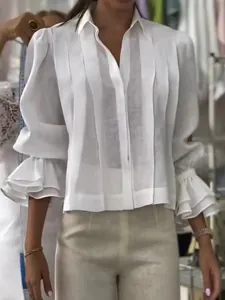 Vista detallada de una blusa transparente plisada blanca con puños con volantes