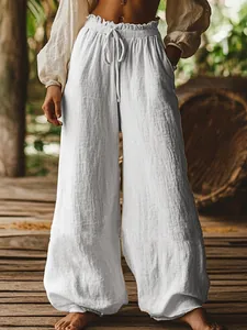 Close-up of white textured wide-leg trousers with elastic drawstring waist and pockets