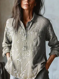 Detailed view of women's loose linen shirt with delicate white floral embroidery