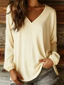 Elegant detail view of a loose cream V-neck blouse with lantern sleeves on a model.