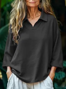 Detail showing the V-neck collar and fabric texture of the black loose shirt.