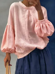 Détail d'un chemisier rose à manches lanternes avec une texture en lin naturel
