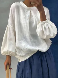 Détail d'une blouse blanche en lin avec des manches lanternes élégantes et un col rond.
