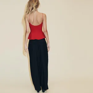 Vue arrière d'un élégant caraco rouge à basque avec un pantalon large noir pour femme.