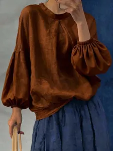 Détail de cette blouse ample en lin marron avec élégantes manches lanternes et col rond.