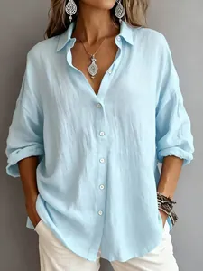 Detail view of a loose fit light blue long-sleeved button-up shirt with linen texture