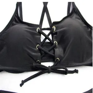 Close-up detail of a black lace-up bikini top featuring metal eyelets and cross straps