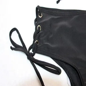 Detailed macro view of black bikini side lace-up ties and golden metal grommets