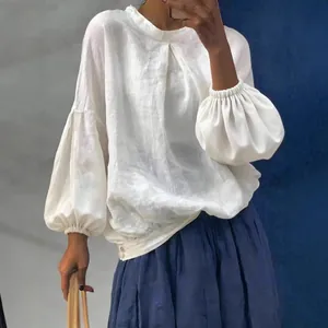 Blouse ample blanche à manches longues en lin avec manches bouffantes et col rond.