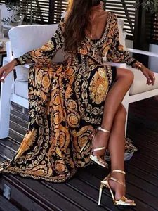 Elegant detail of a long-sleeve V-neck slit maxi dress with gold baroque patterns