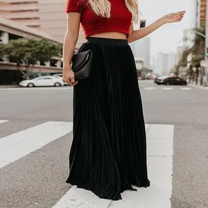 Outdoor street style shot of a woman wearing a black high-waisted pleated maxi skirt.