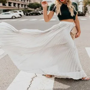 Elegant white pleated maxi skirt shown with a flowing, wide hem in a street view.