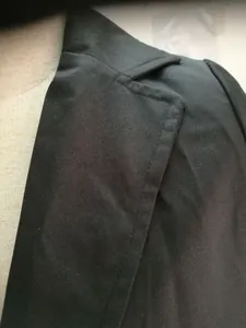 Dettaglio del risvolto di un blazer professionale da donna con cuciture fini su tessuto nero