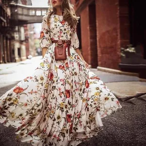 Street style shot of a woman in a floral maxi dress with a brown belt in an urban alleyway.