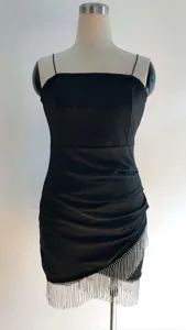 Détail d'une robe moulante noire avec des franges argentées scintillantes à l'ourlet.