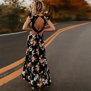Vue arrière d'une robe longue fleurie noire avec un dos nu en dentelle sur une route au crépuscule