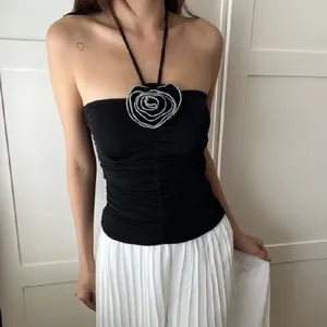Detail view of black halter top featuring a large silver rose flower embellishment.