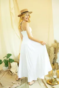 Elegant white maxi beach skirt shown on model with brown hat in a natural studio