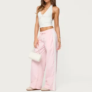 Close-up detail of women's pink loose straight track pants with white side stripes