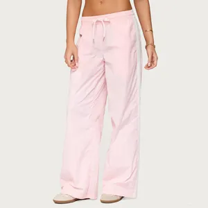 Close-up of stylish women's pink loose drawstring trousers with white side stripes.