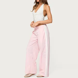 Detailed side view of women's pink wide-leg drawstring pants with white side stripes