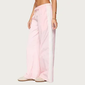 Detailed side view of pink wide-leg drawstring pants featuring classic white side stripes