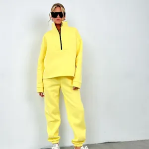 Donna che indossa una tuta giallo brillante con felpa con mezza zip e pantaloni jogger sportivi