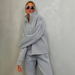 Modella con una felpa grigia con collo a lupetto e pantaloni sportivi abbinati