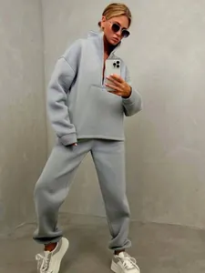 Dettaglio di un set da donna con felpa grigia a collo alto e pantaloni jogger coordinati