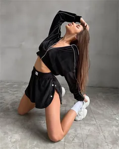 Detailed view of women's black two-piece sports set with zip jacket and side-button shorts