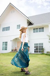 Bohemian peacock print maxi skirt flowing gracefully in a sunny outdoor garden