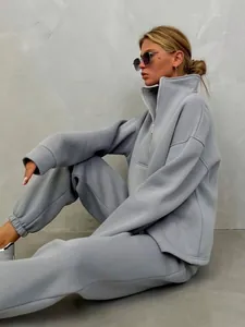 Vista laterale della donna che indossa tuta grigia a due pezzi con collo alto e jogger