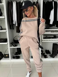 Full body view of a beige women's two-piece striped tracksuit in a modern closet.