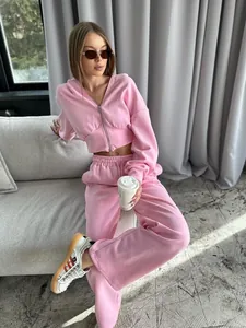 Professional detail view of a stylish women's pink two-piece tracksuit with zip-up hoodie.
