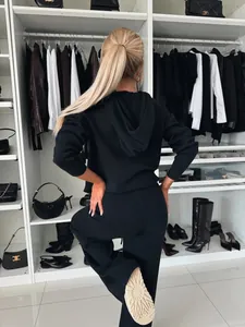 Vue de dos d'une femme portant un survêtement noir à capuche dans un dressing élégant