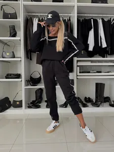 Close-up of a women's black two-piece tracksuit with white stripes in a modern closet.
