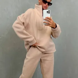 Dettaglio della tuta da donna beige oversize con collo alto e design a mezza zip