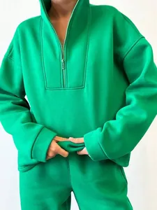 Vista dettagliata della tuta verde brillante da donna con felpa oversize con mezza zip e pantaloni.