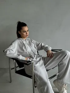 Chic woman wearing light grey two-piece lounge set with zip hoodie and wide-leg pants