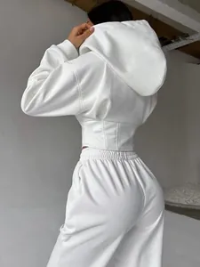 Vista posteriore di un set chic con felpa bianca e pantaloni con vita a corsetto.
