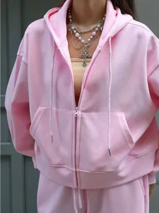 Close-up detail view of a soft pink cotton zip-up hoodie with front pocket and hood