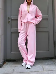 Woman in a pink two-piece tracksuit with a zip-up hoodie and wide-leg jogger pants