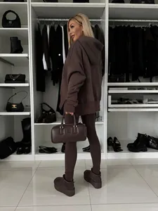 Conjunto de sudadera con capucha extragrande y leggings marrón para mujer en un vestidor.